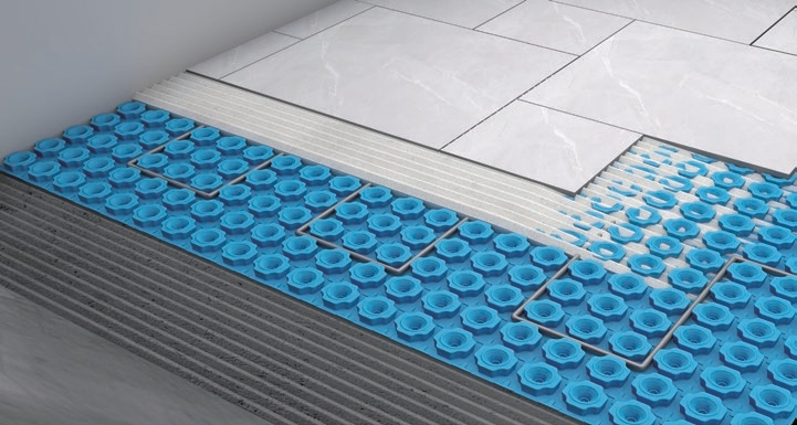 Large-format tile being set over a blue uncoupling mat on a combed thin-set bed